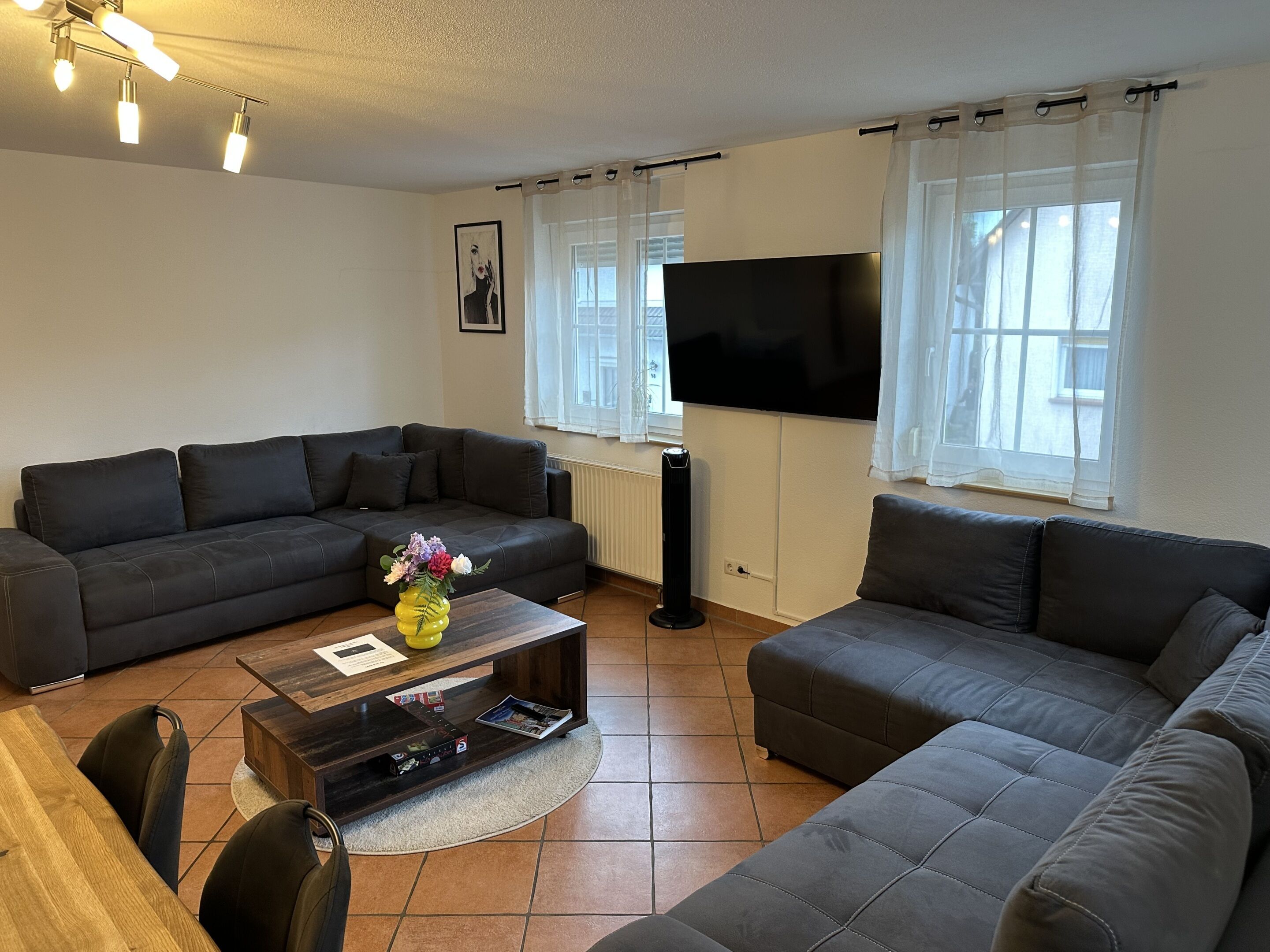 A living room with a sofa set, a coffee table, a TV, and a window with curtains.