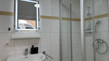 Une salle de bain avec un lavabo, un miroir et une douche.