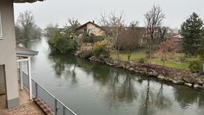 A river with houses on one side and a building with a balcony on the other.