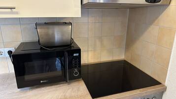 Una cocina con un microondas negro, un horno empotrado y una campana extractora de acero inoxidable.