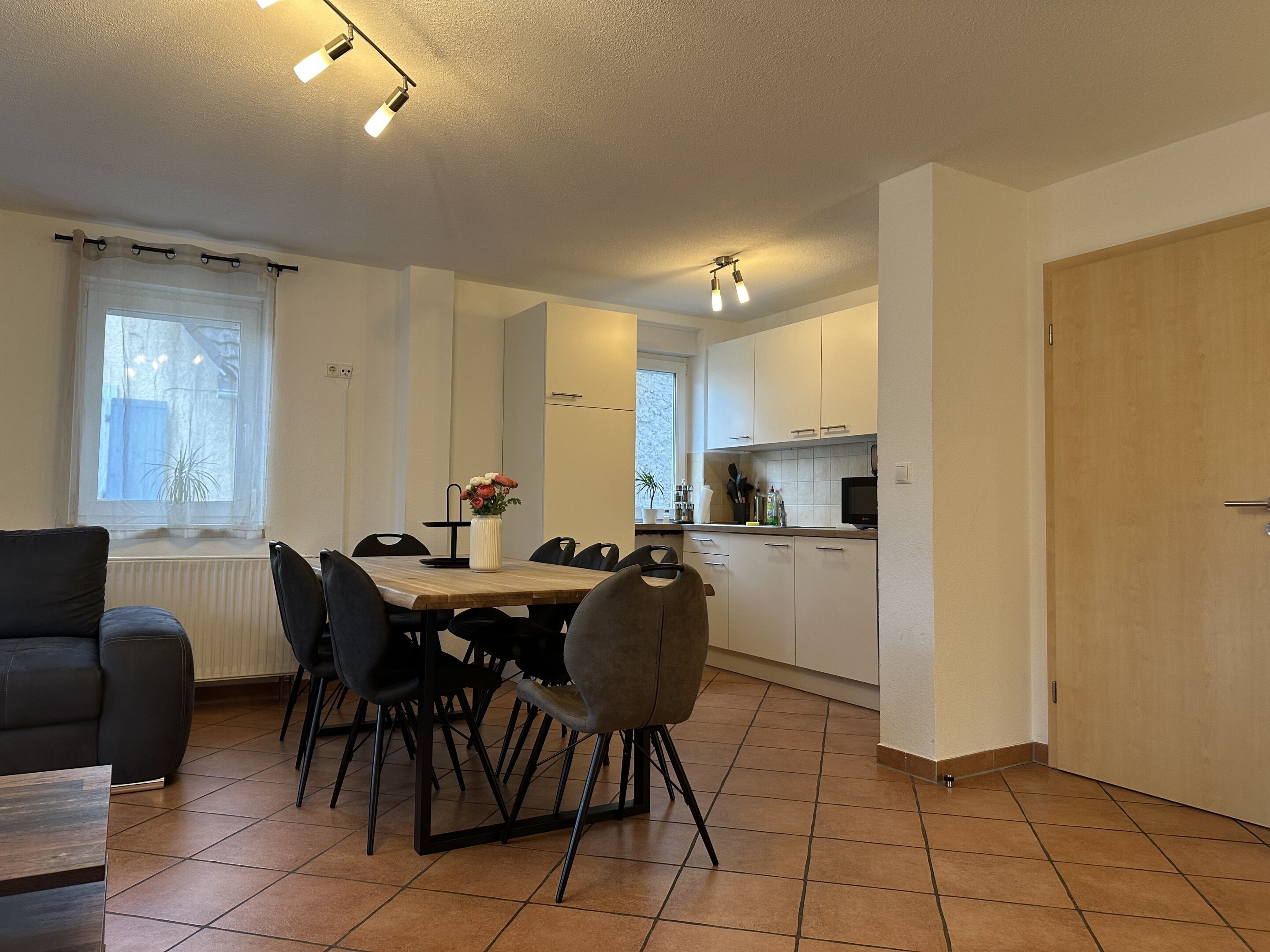 Een moderne keuken met witte kasten, een eettafel met stoelen en een televisie.