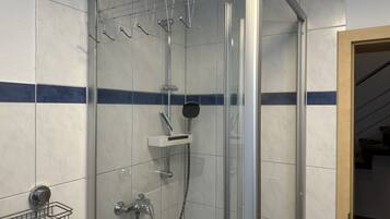 A shower with a glass door, a hand dryer, and a towel rack.