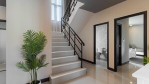 Un interior moderno con una escalera, una planta en maceta y un acceso a otra habitación.