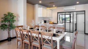 Un comedor moderno con una mesa blanca, sillas de madera y una planta en maceta.