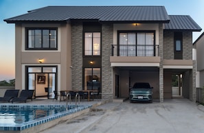 A two-story house with a swimming pool, a covered garage, and a balcony.