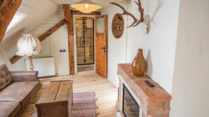 Un acogedor espacio tipo loft con techo de madera, chimenea, sofá y alfombra estampada.