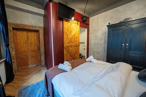 Una habitación de hotel con una cama, un armario de madera, un espejo y una puerta.