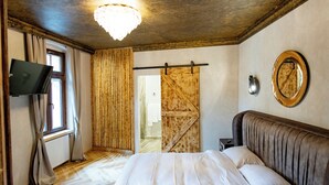 Un dormitorio con cama, televisión, puerta de madera y candelabro.