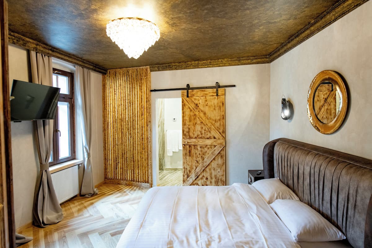 Un dormitorio con cama, televisión, puerta de madera y candelabro.