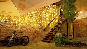 Una pared de piedra con luces colgantes, una bicicleta y una escalera.