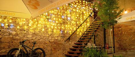 Una pared de piedra con luces colgantes, una bicicleta y una escalera.
