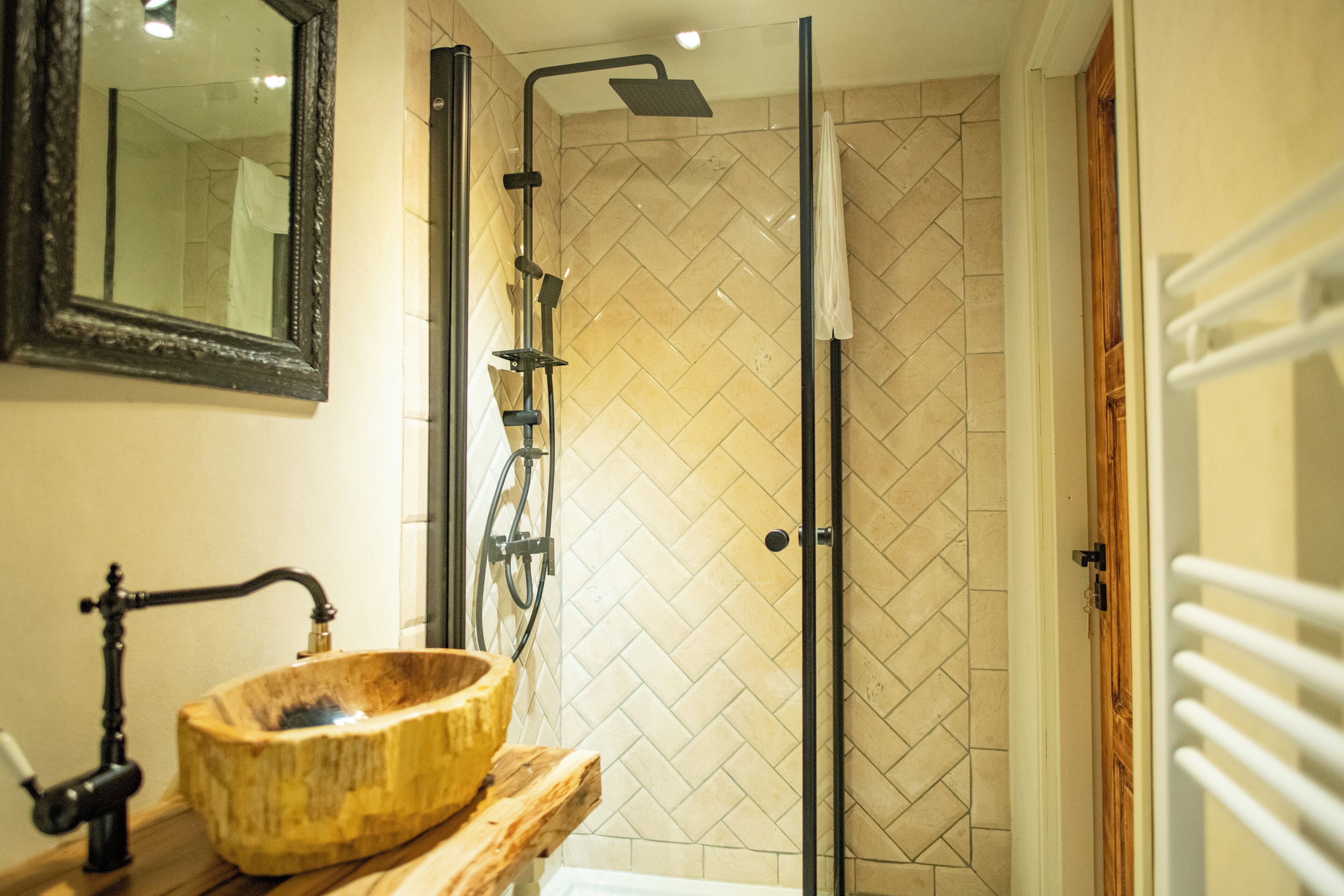 A bathroom with a wooden basin, a mirror, and a shower with a herringbone tile pattern.