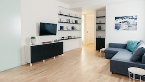 A modern living room with a black console table, a flat-screen TV, and a grey sectional sofa.