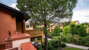 Une cour avec un grand arbre, un espace extérieur abrité avec des sièges, et une vue sur les bâtiments environnants.