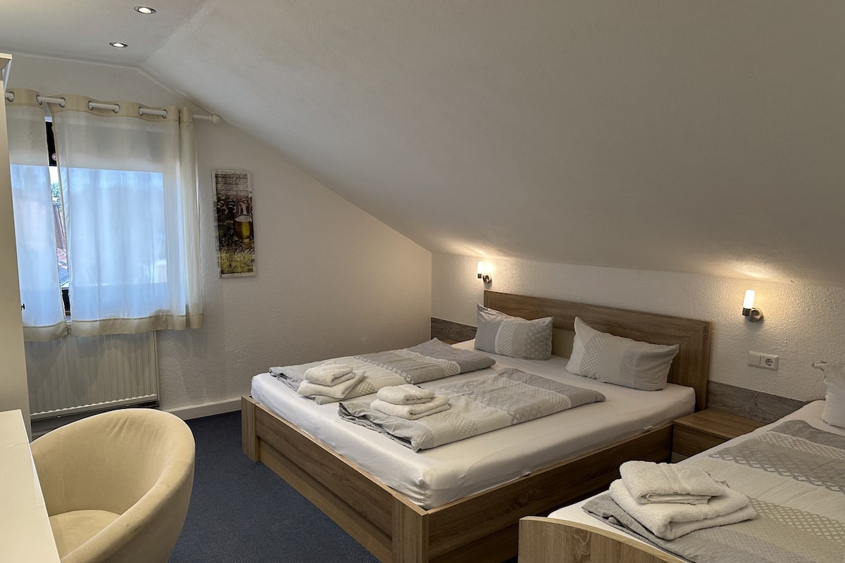 Una camera da letto con un letto di legno, due comodini, una sedia e una finestra con tende.