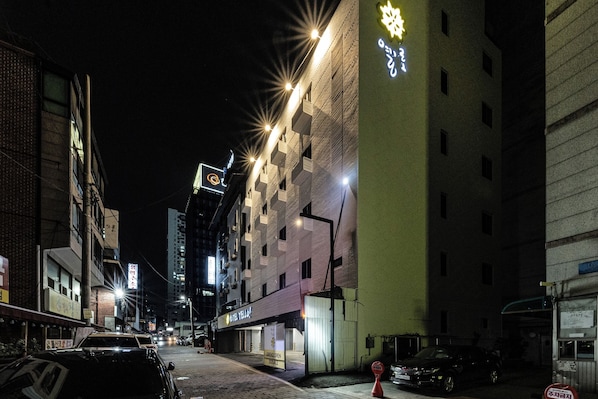 A nighttime street view with a building featuring a neon sign and illuminated windows. - hotelyello Guri (Guri)