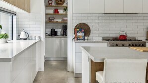 A modern kitchen with white cabinetry, a gas stove, and a coffee machine.