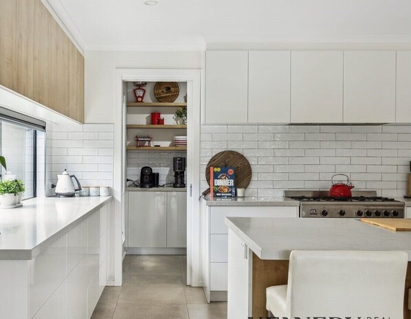 A modern kitchen with white cabinetry, a gas stove, and a coffee machine. - Resort 69 - Lakeview with privacy (Yarrawonga)