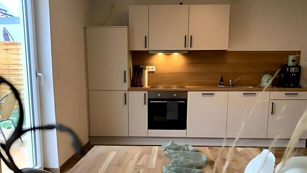 Une cuisine moderne avec des armoires blanches, un plan de travail en bois et un four encastré.