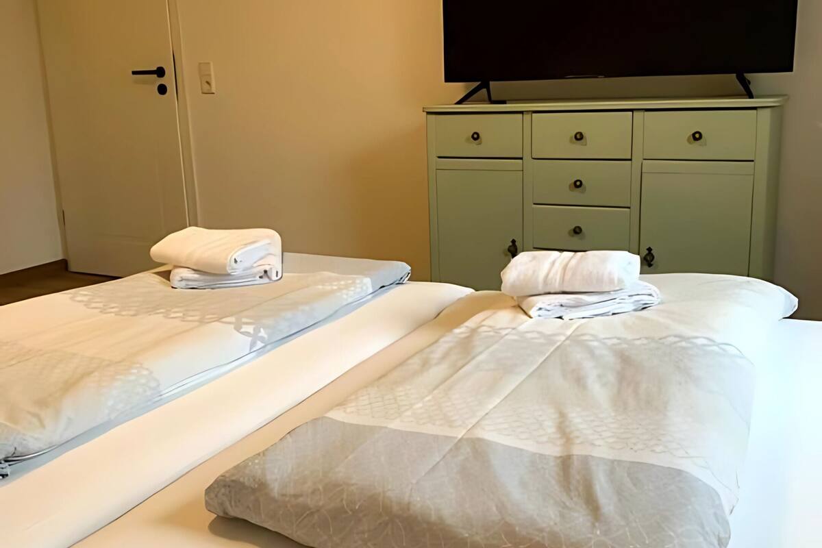 A hotel room with two beds, a television, and a green dresser.