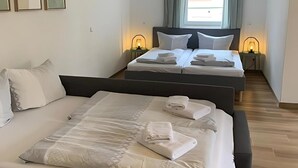 Une chambre d’hôtel avec deux lits, une petite table et une fenêtre avec des rideaux.