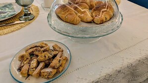 A dining table with a glass dome cover, a plate of croissants, and a bowl of biscotti. - B&B IL GLICINE (Coperchia)