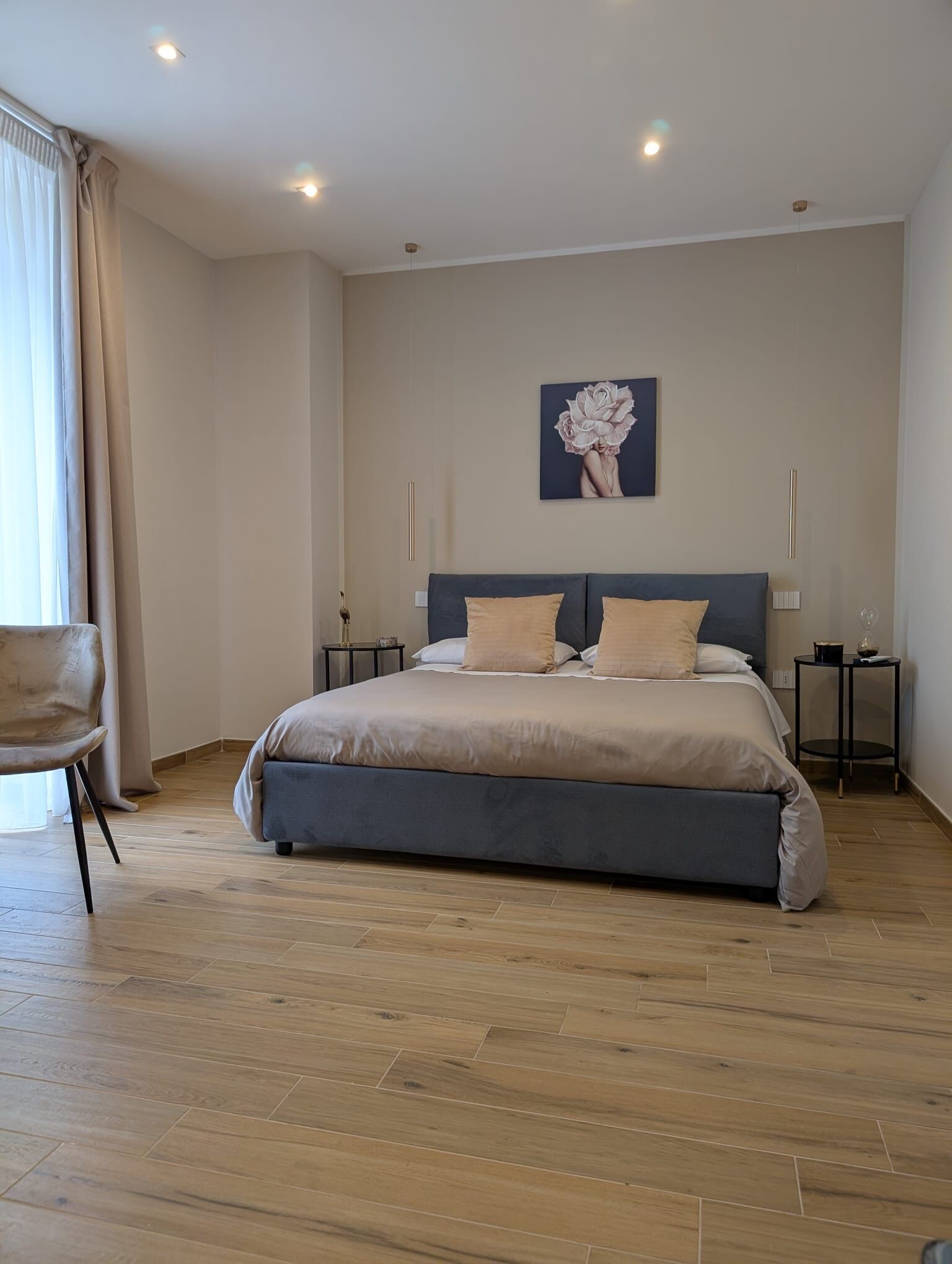 Een slaapkamer met een groot bed, een stoel en een schilderij aan de muur.