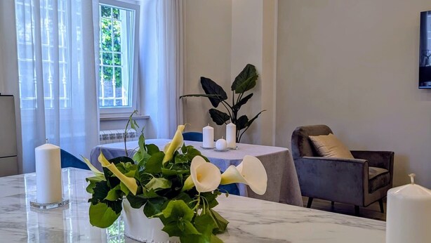 A modern dining area with a marble table, white candles, and a potted plant. - B&B IL GLICINE (Coperchia)
