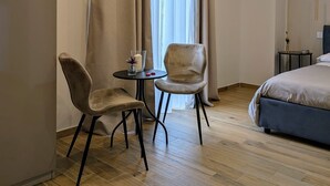 A hotel room with a bed, two chairs, a small table with a candle, and a window with curtains. - B&B IL GLICINE (Coperchia)