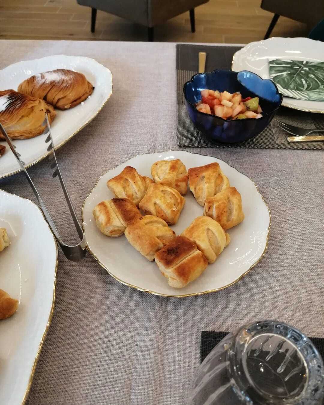 Una tavola imbandita con dolcetti, un cestino di frutta e un bicchiere.