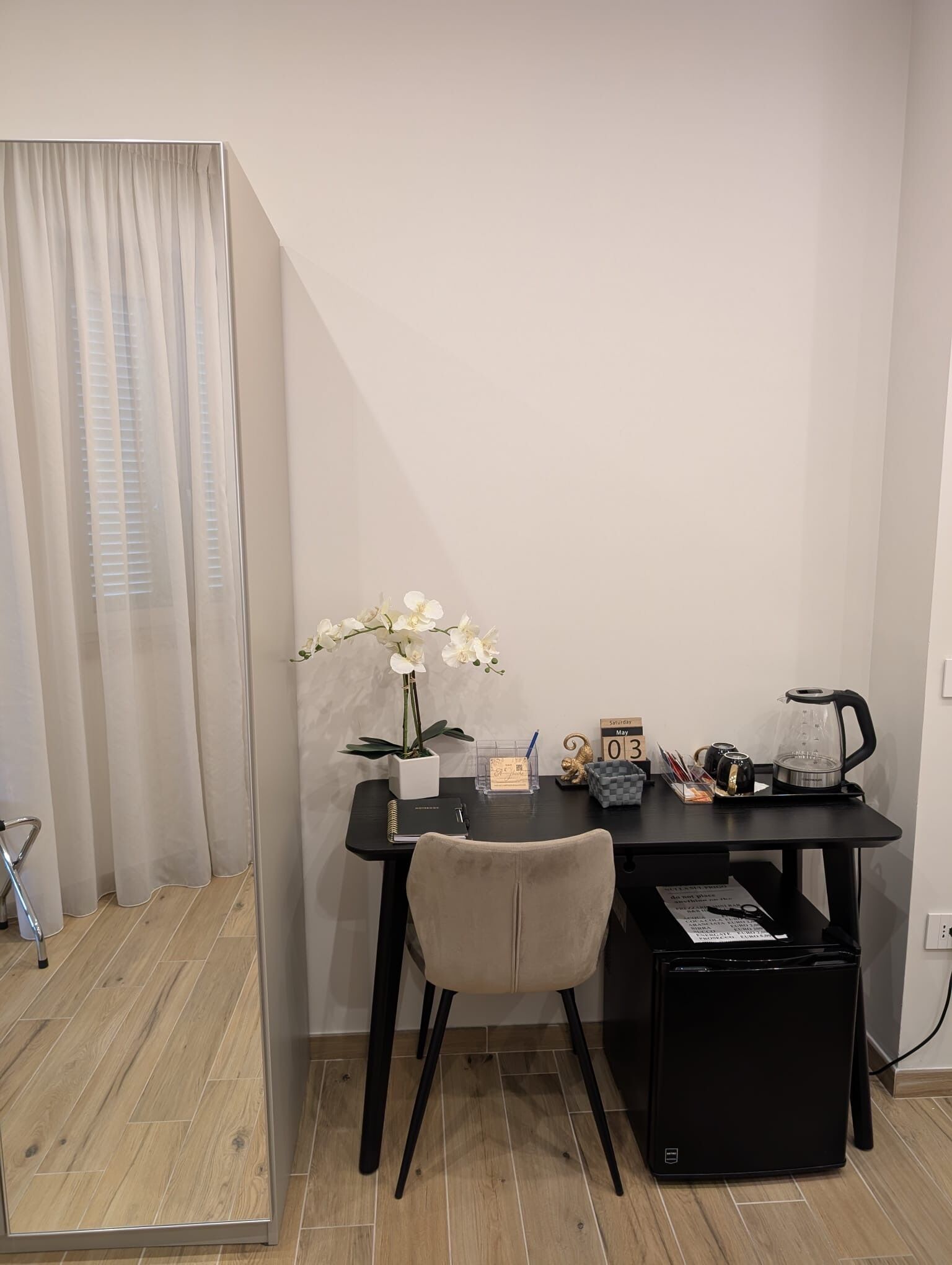 A small, tidy room with a desk, chair, and a potted orchid.