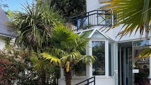 A modern building with a glass conservatory, surrounded by lush greenery and a well-maintained garden. - Adonis Cottage La Baule (La Baule-Escoublac)