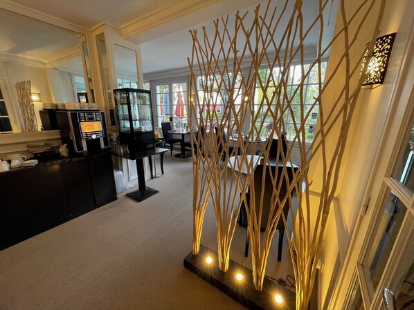 Un moderno vestíbulo de hotel con una barra de café, zona de estar y una estructura decorativa de madera.