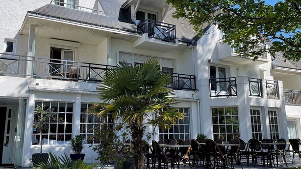 A two-story building with a balcony and outdoor seating area. - Adonis Cottage La Baule (La Baule-Escoublac)