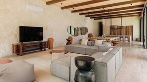 Een ruime woonkamer met een grote hoekbank, een flatscreen televisie en een houten entertainmentkast.