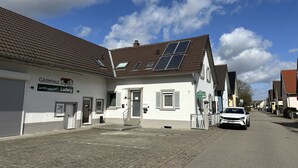 Ein Gebäude mit Solaranlage, einem Schild mit der Aufschrift 'Gästehaus Ludwig' und einer gepflasterten Straße.