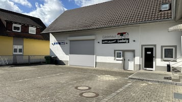 Ein Gebäude mit einem Ziegeldach, einer Garagentür und einem Schild mit der Aufschrift 'Gästehaus Ludwig'.