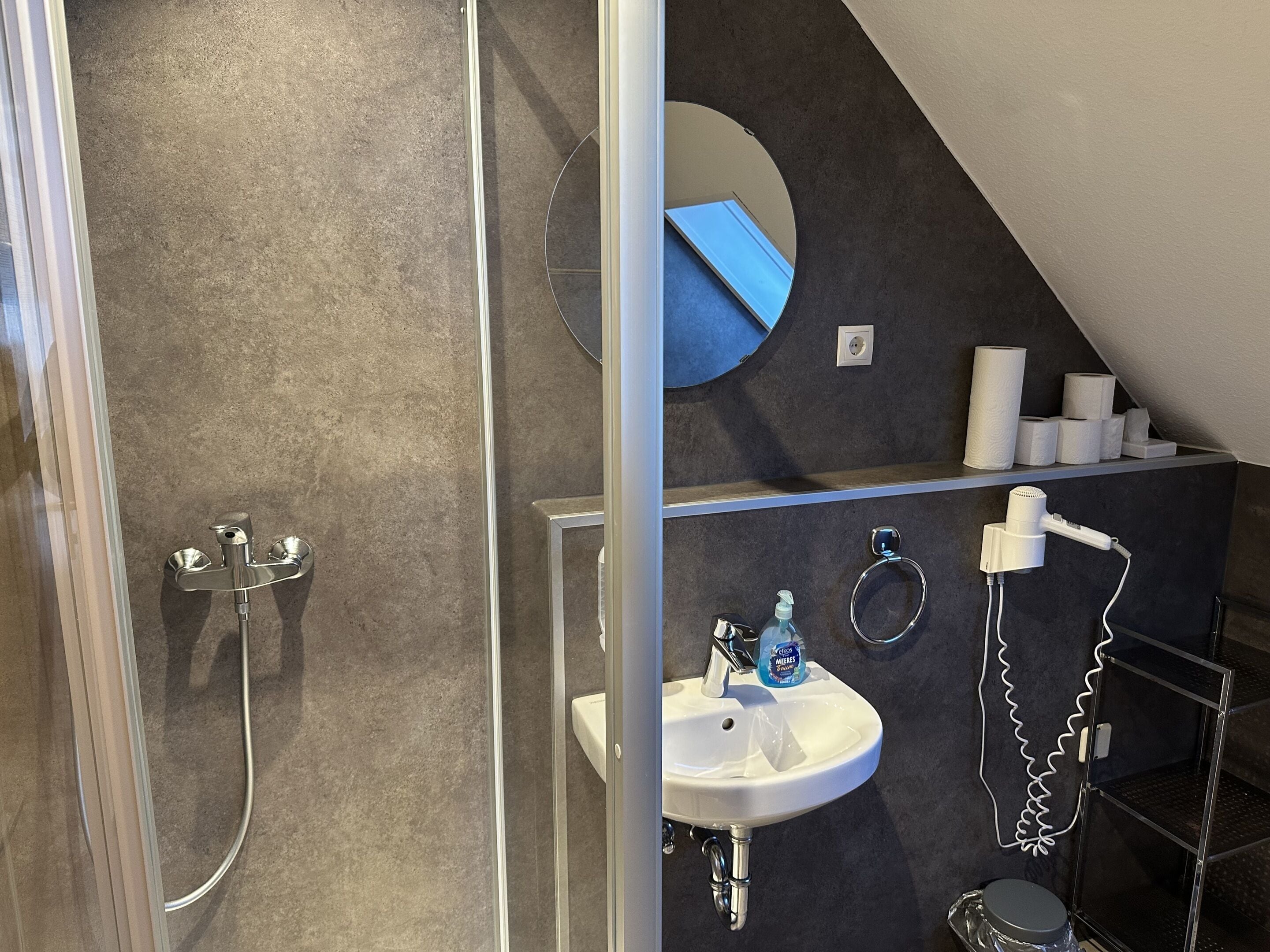 Une salle de bain moderne avec une douche à parois de verre, un lavabo avec un miroir et un porte-serviettes.