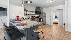 Eine moderne Küche mit Granit-Arbeitsplatten, Edelstahlgeräten und einer zentralen Kochinsel mit Barhocker.
