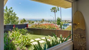 A balcony with a view of a cityscape, a wooden fence, and a surfboard leaning against the wall.