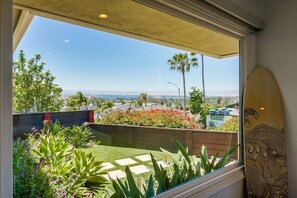 A balcony with a view of a cityscape, a wooden fence, and a surfboard leaning against the wall.