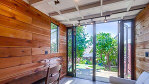A room with wooden walls, a bench, a sofa, and a sliding glass door leading to a garden.