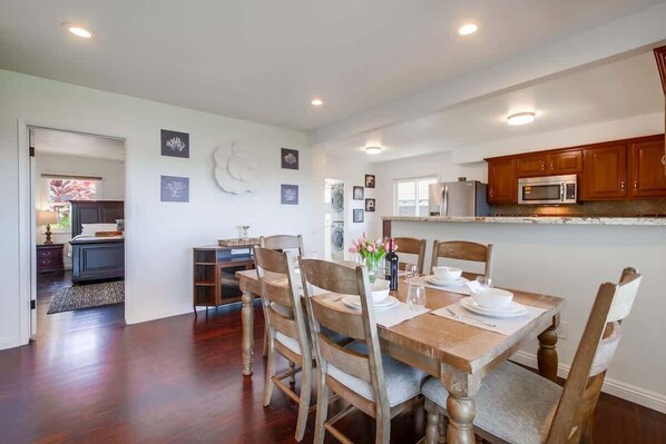 A dining area with a wooden table set for four, surrounded by wooden chairs.