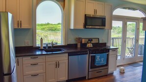 Una cocina con armarios blancos, un refrigerador de acero inoxidable, un microondas y un horno.