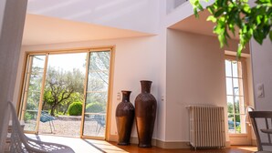 Een kamer met een grote schuifdeur die uitkomt op een buitenruimte, twee grote vazen op een houten tafel, en een radiator op de vloer.
