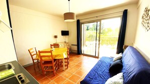 A compact living space with a dining area, a kitchenette, and a sofa. - "Le Paloma" swimming-pool-clim-parking (La Ciotat)