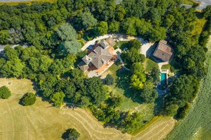 Oversigtsbillede af et boligområde med flere huse, en swimmingpool og grøn bevoksning omkring.