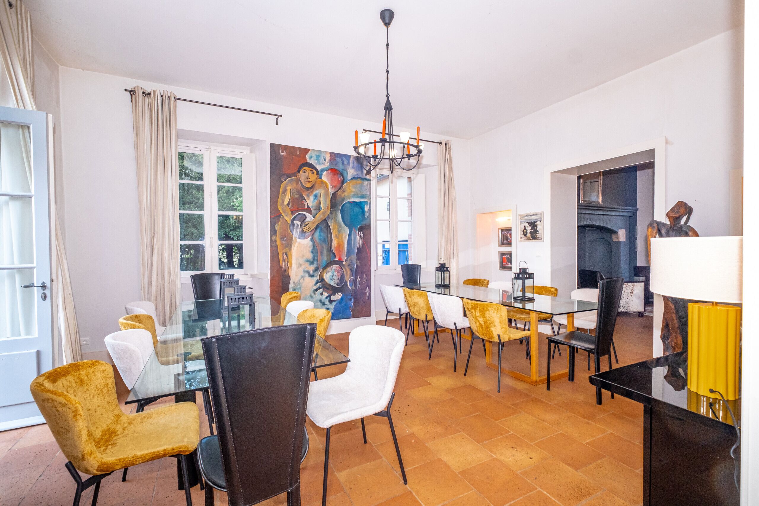 A dining area with a glass table, chairs, and a mural on the wall.