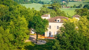 Une villa dotée d’un toit en tuiles, entourée d’une végétation luxuriante et de champs.