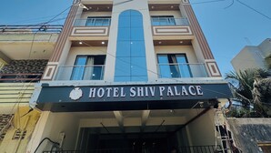 Un hotel llamado "Hotel Shiv Palace" con una fachada moderna, amplios ventanales y una entrada destacada.